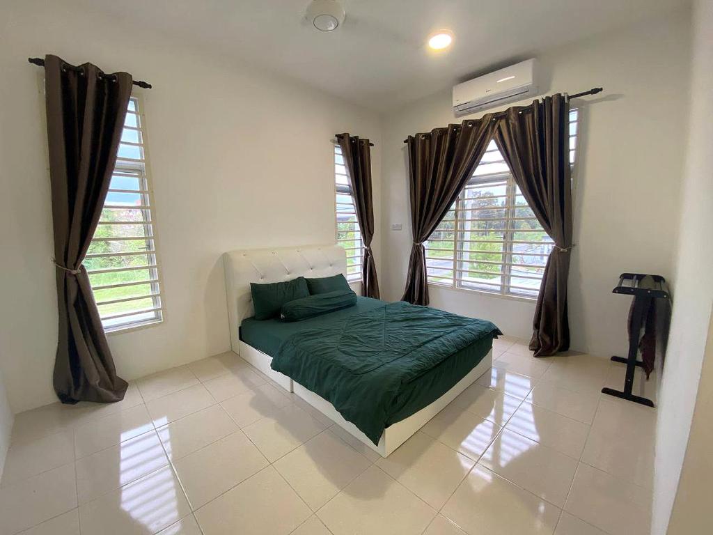 a bedroom with a green bed in a room with windows at De Nadia Homestay in Port Dickson
