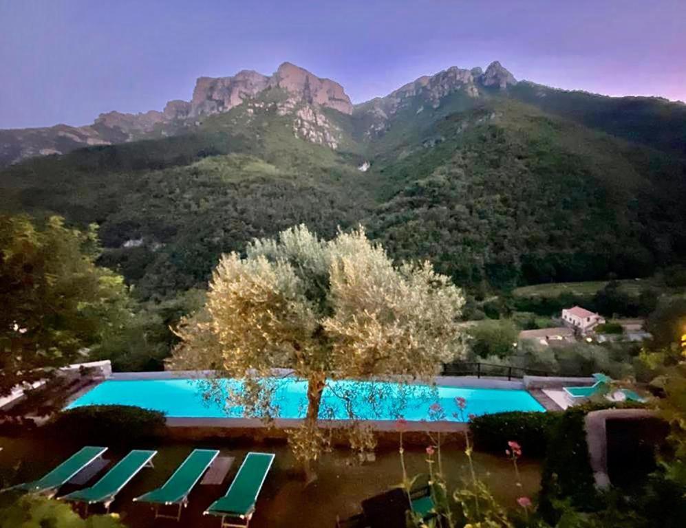 una piscina con sedie, un albero e le montagne di Medieval mountain setting with private garden a Colletta