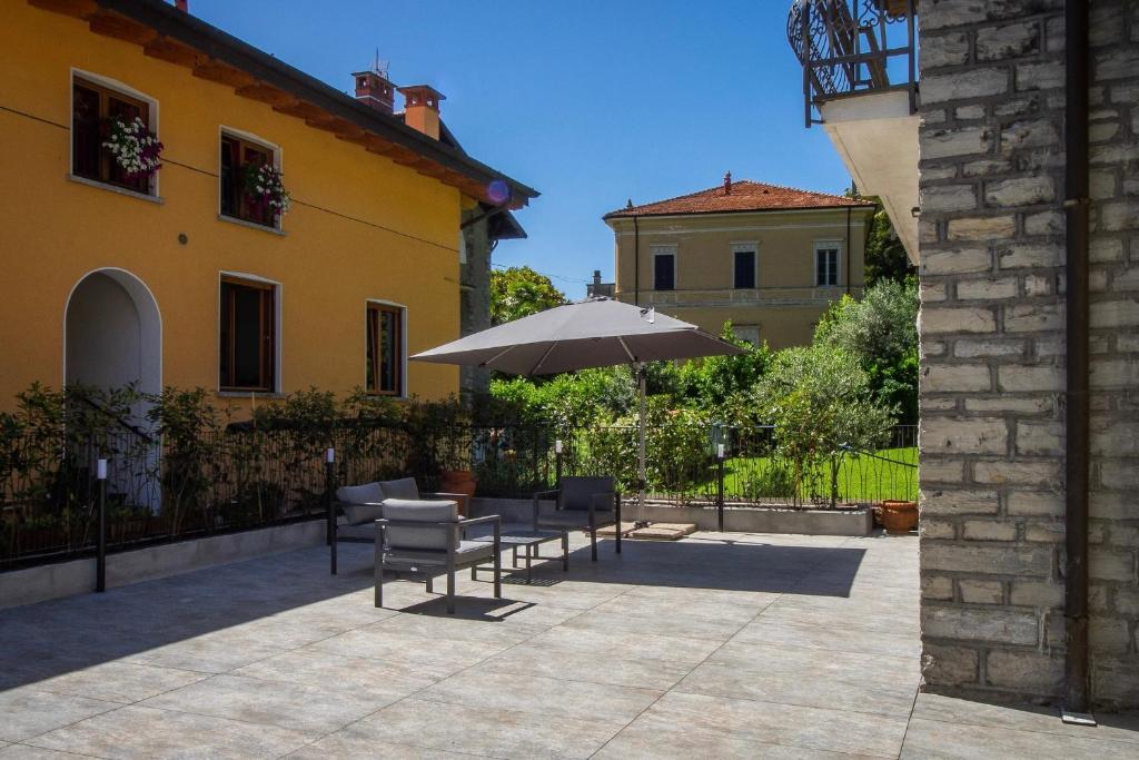 un patio avec une table et un parasol dans l'établissement Villa Senagra Holidays Lake Como, à Menaggio