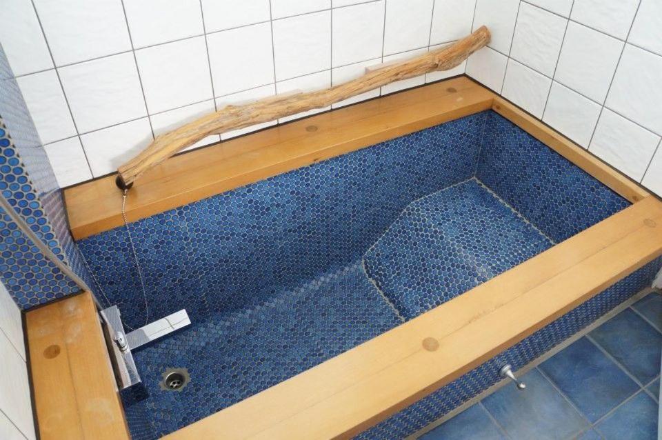 a bath tub with a wooden frame and blue tiles at 微笑58民宿 Smile 58 B&amp;B in Puli