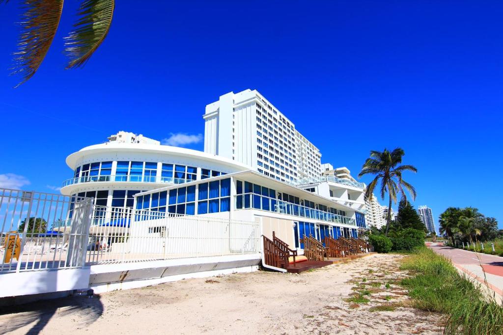 a large white building with blue windows on a beach at Miami Beach Apartments by MiaRentals in Miami Beach