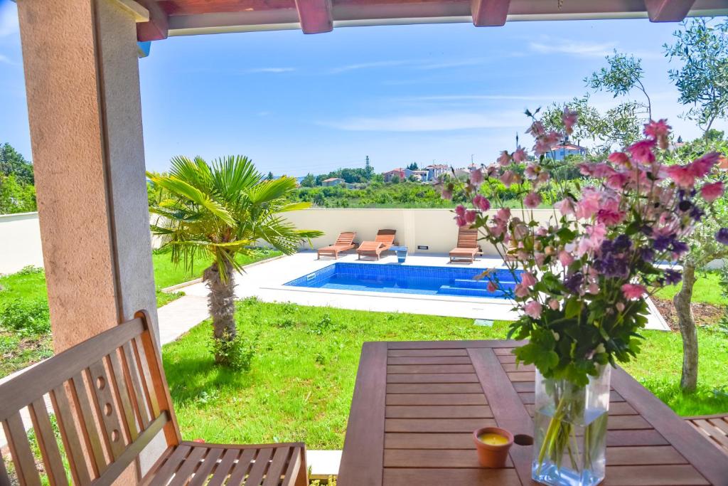 una mesa con un jarrón de flores en un patio en Aptartment - Istrian Dream with swimming pool en Peroj