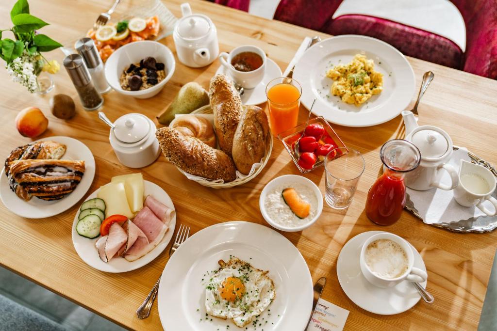 ein Tisch mit Tellern voller Frühstücksspeisen darauf in der Unterkunft Naturhotel Lärchenhof in Ramsau am Dachstein