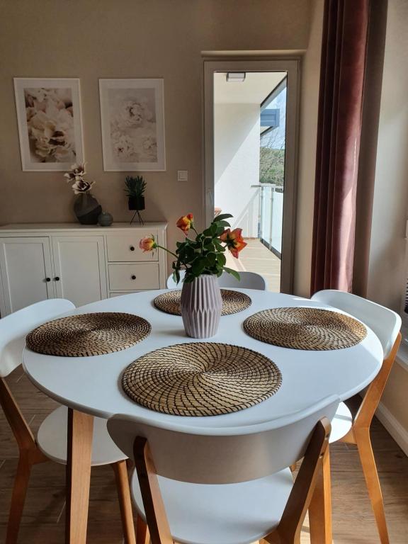 una mesa blanca con sillas y un jarrón con flores. en Zamiejska Modern Apartments, en Słupsk