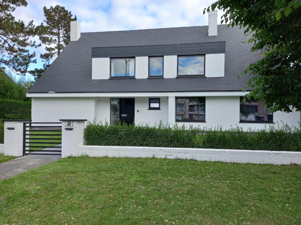 een wit huis met een zwart dak bij The White Villa in Blankenberge