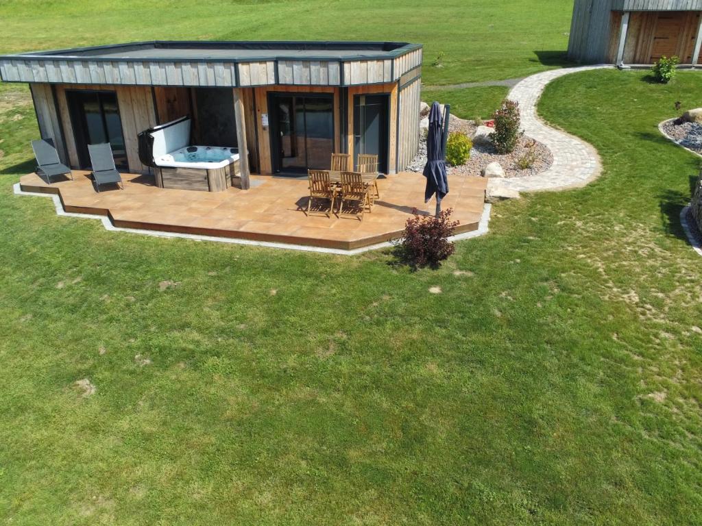 vistas a una casa con terraza y bañera de hidromasaje en Nature Cottage Vosges Spa Le Cerf, en Anould