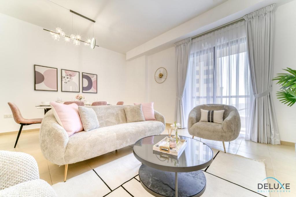 ein Wohnzimmer mit einem Sofa, Stühlen und einem Tisch in der Unterkunft Impeccable 2BR at Bahar 2 JBR by Deluxe Holiday Homes in Dubai