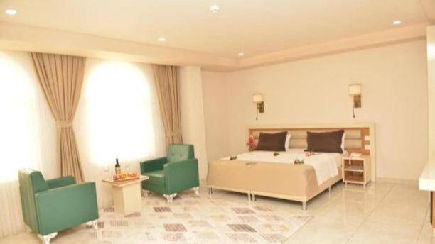 1 dormitorio con 1 cama y 2 sillas verdes en Akitu Hotel, en Midyat