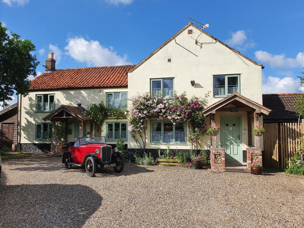 a red car parked in front of a house at The Elms in East Harling