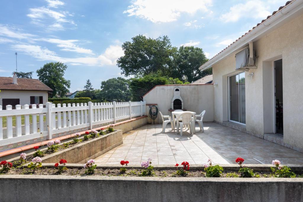une terrasse avec une clôture blanche, une table et des chaises dans l'établissement Maison Soustons proche mer, à Soustons