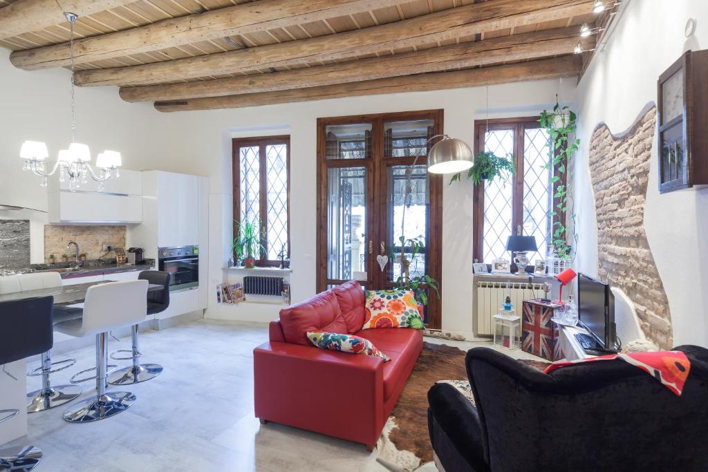 a living room with a red couch and a kitchen at Residenza Principe Amedeo City Center free parking in Verona