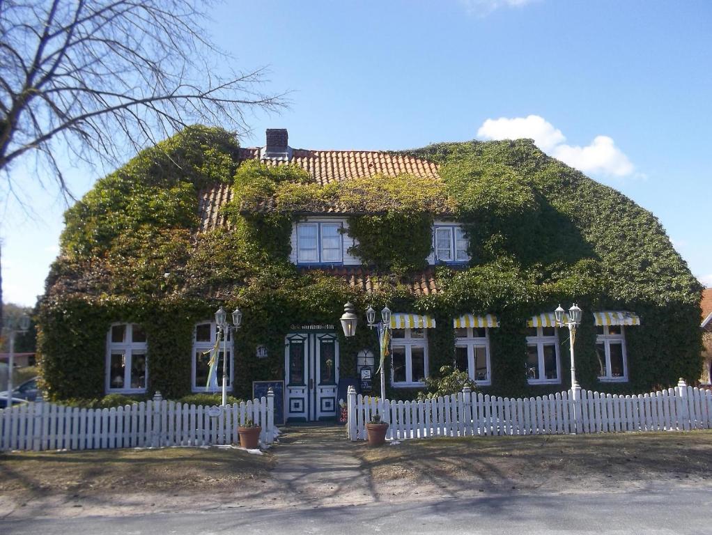 a house covered in ivy with a white fence at Lütte Pension in Egestorf