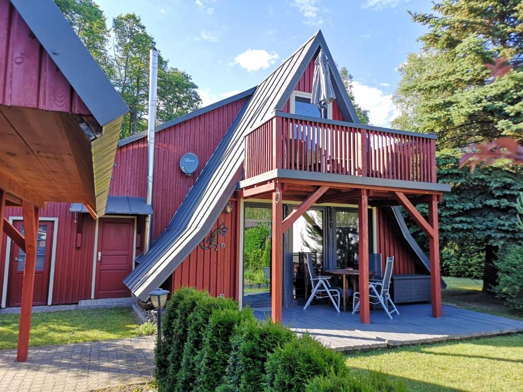 a red barn with a deck and a table at Ferienhaus am Lübbesee in Milmersdorf