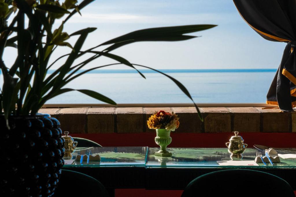 uma mesa com um vaso com flores em cima em Hotel Villa Carlotta em Taormina