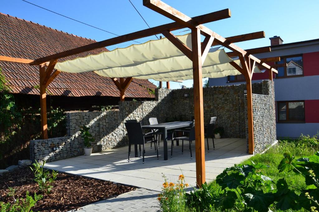 een houten pergola met een tafel en stoelen eronder bij apartmány LUHA in Luhačovice