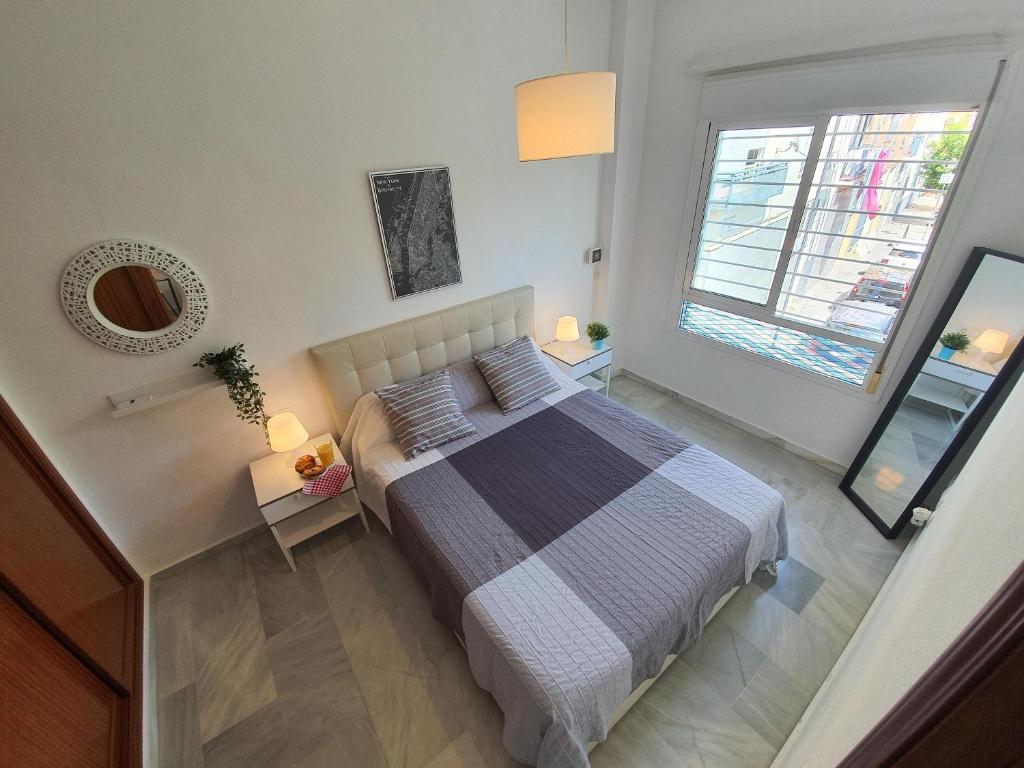 Un dormitorio con una cama grande y una ventana en Los Cristos, en Málaga
