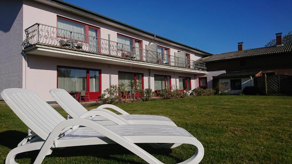 Deux chaises blanches assises dans l'herbe devant un bâtiment dans l'établissement Ostseehotel SchleiFee, à Kappeln
