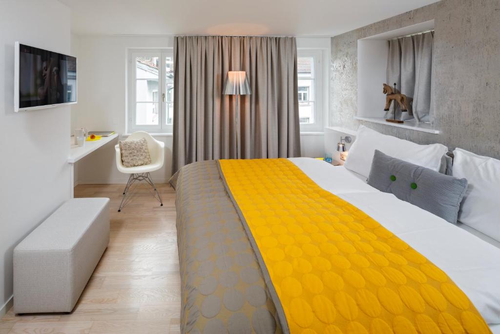 a bedroom with a large bed with a yellow blanket at Hotel Rössli in Zürich