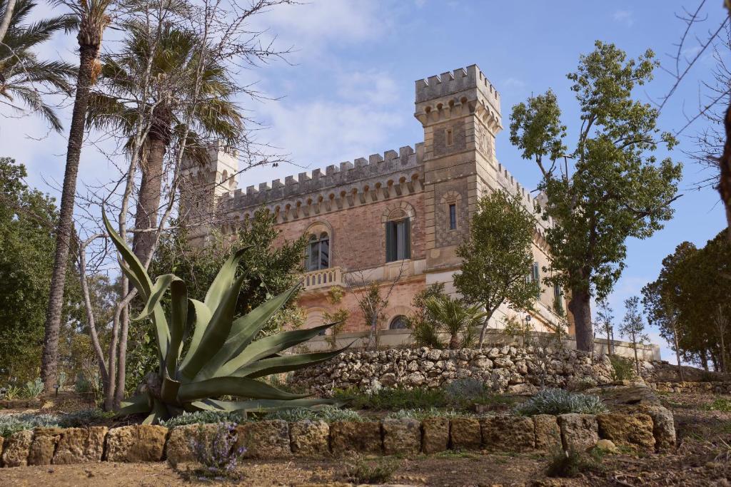 um antigo edifício de pedra com uma palmeira em Castle Elvira em Trepuzzi