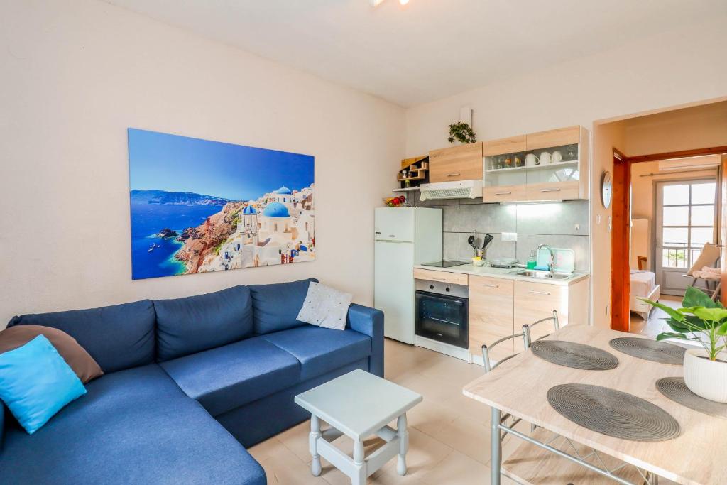 sala de estar con sofá azul y cocina en Calma Luxury Apartments #2 Sozopoli in Halkidiki, en Sozopoli