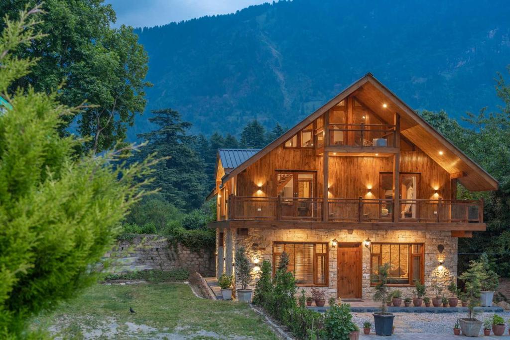 a log home with a deck and a mountain at StayVista at The Artisans' Chalet with Indoor Jacuzzi in Manāli