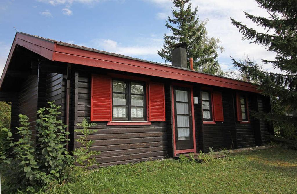 a small wooden house with red trim in the grass at Ferienpark Lauterdörfle 4 in Hayingen