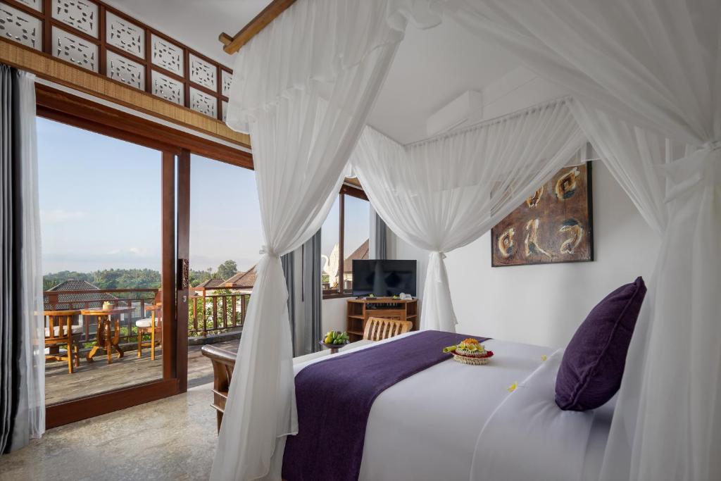 a bedroom with a white bed and a balcony at Swan Paradise A Pramana Experience in Gianyar