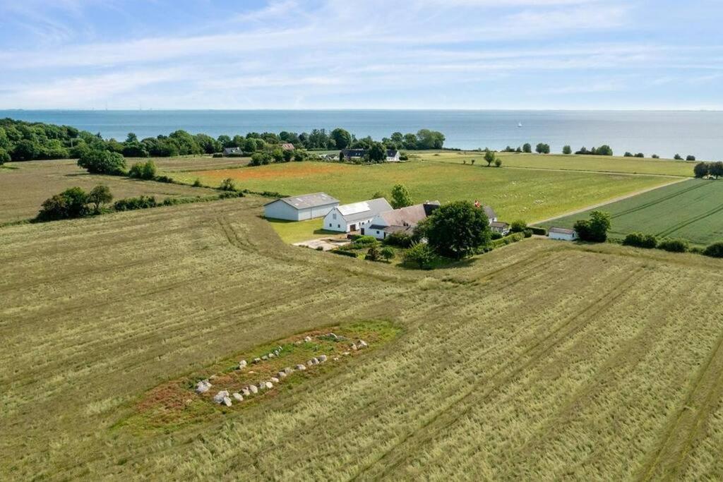 an aerial view of a field with a house and a farm at Idyllisk gård med ro, plads og havudsigt in Hesselager