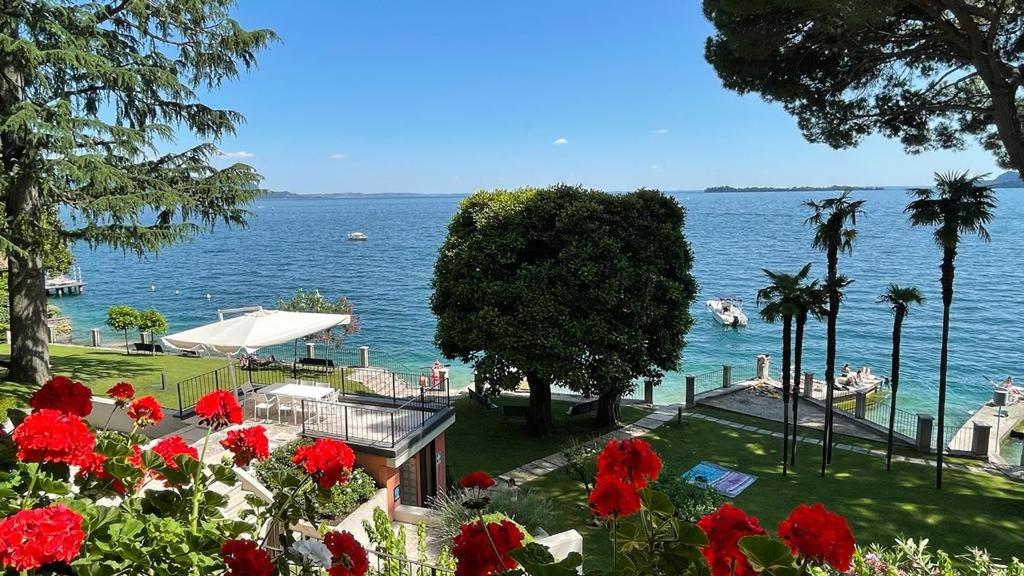 - une vue sur une étendue d'eau ornée de fleurs rouges dans l'établissement Casa Jessika, à Gardone Riviera