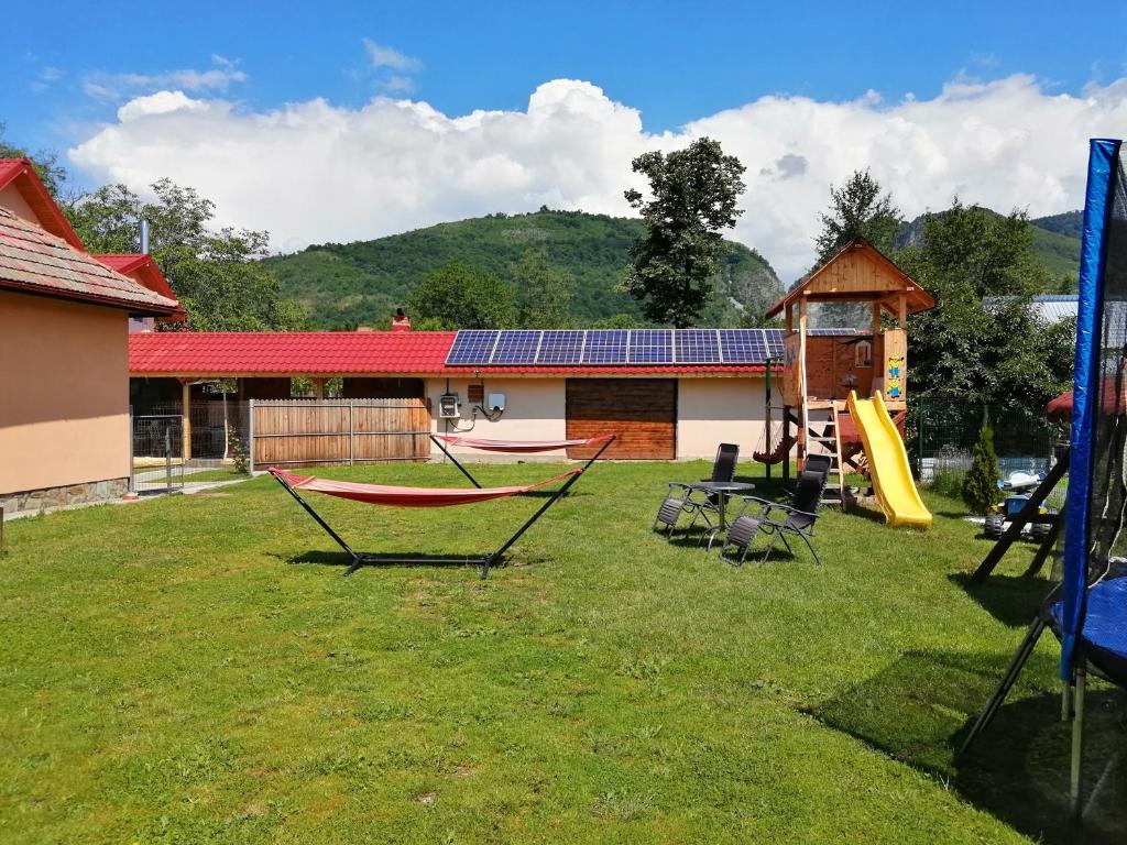 einen Hof mit einem Spielplatz mit Rutsche und einem Haus in der Unterkunft Casa Stefi si Alexia in Polovragi