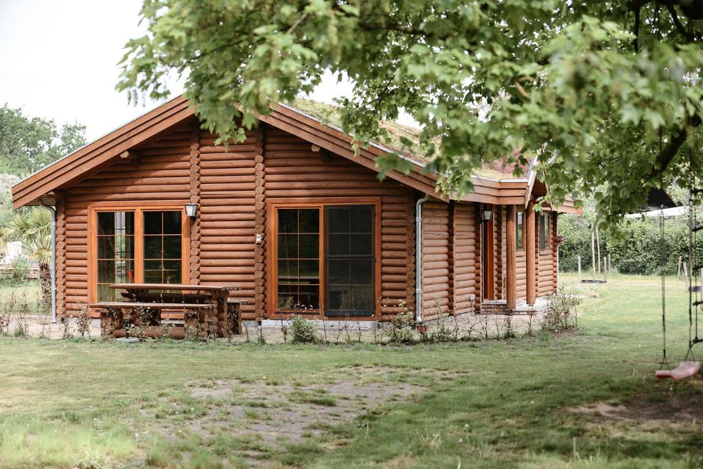 uma cabana de madeira com um banco à frente em Bij de Appelhof em Valkenswaard