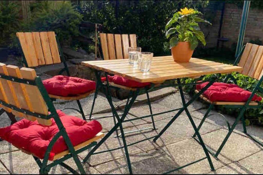 una mesa de madera y sillas con cojines rojos en el patio en Ferienwohnung Lavendel, en Waren