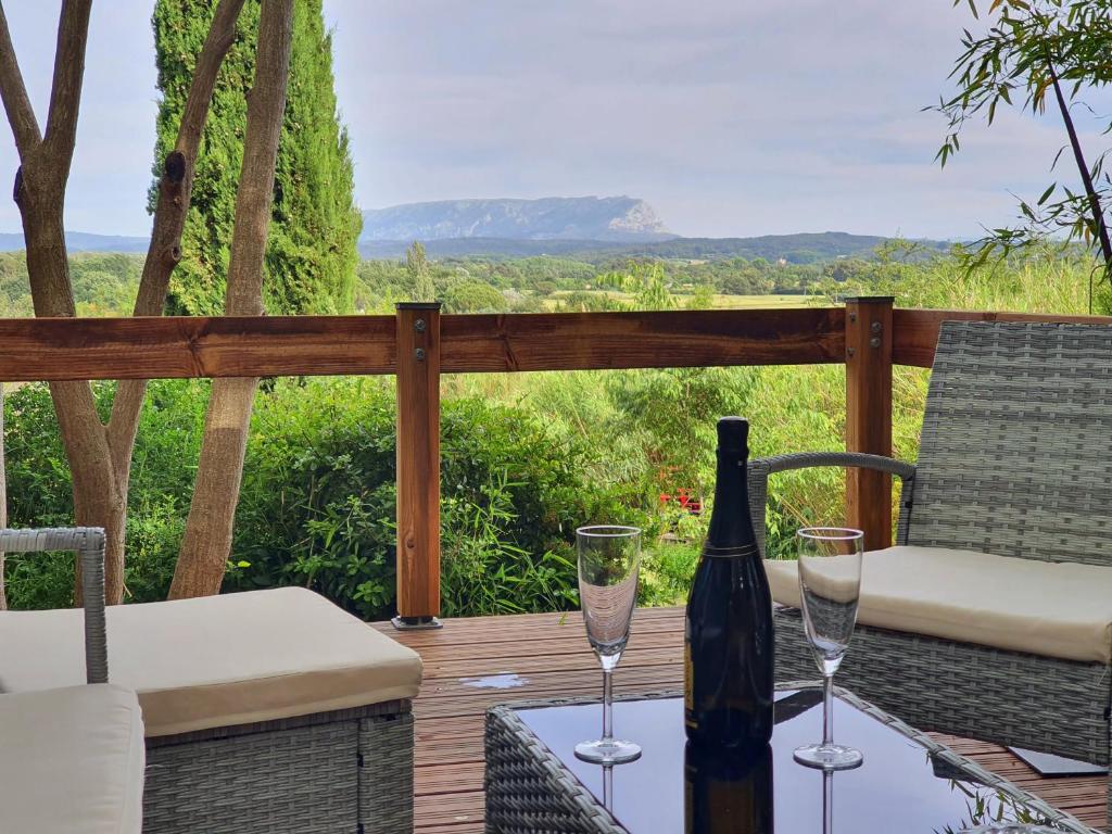 a bottle of wine and two glasses on a deck at Adorable chalet avec jacuzzi privatif in Aix-en-Provence