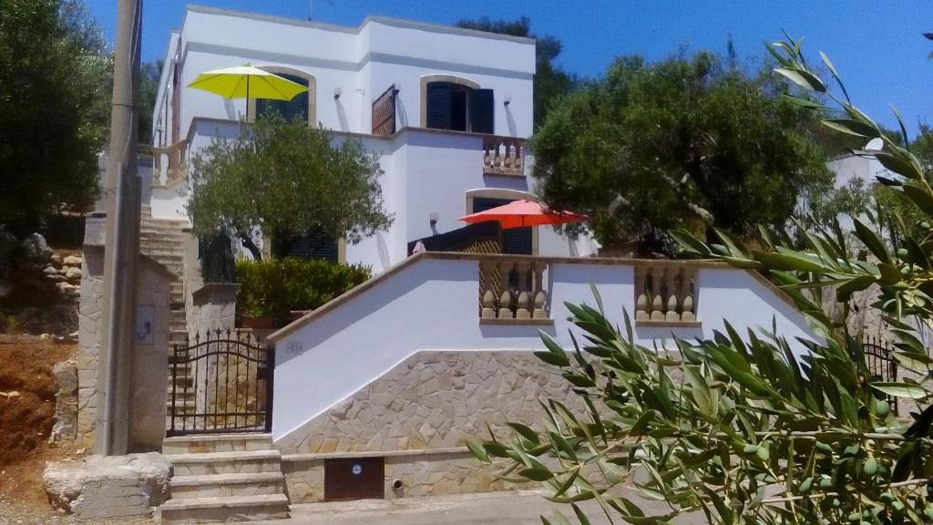 Casa blanca con 2 sombrillas en el balcón en Casa vacanza Marina di Andrano zona Grotta Verde, en Andrano