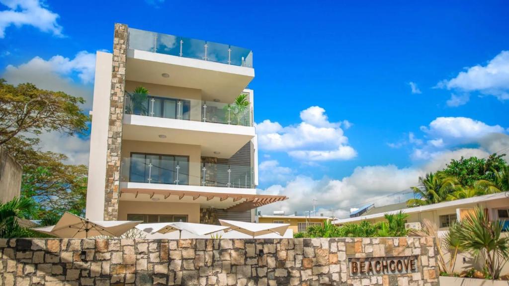 Bâtiment en aominium avec un mur de retenue en pierre devant lui dans l'établissement PEREYBERE -Charming 2 bedrooms apartment- WITH POOL - BEACHCOVE Apartments, North Living, APT 8, à Pereybere