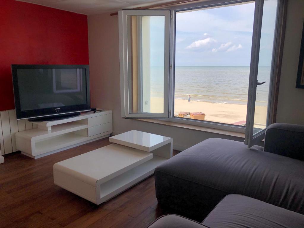 a living room with a television and a view of the beach at Villa ALOHA in Bray-Dunes