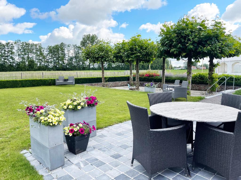 een patio met een tafel, stoelen en bloemen bij Hotel het Elsland in Wervik