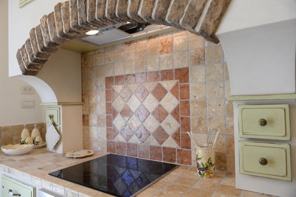 a kitchen with a sink and a tile wall at Holiday Home La Leccina in Erchie