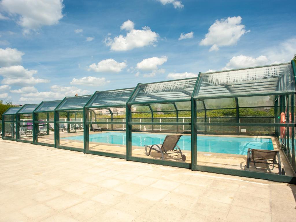 a large swimming pool with a glass greenhouse at Vacancéole - Le Duguesclin in Dinan