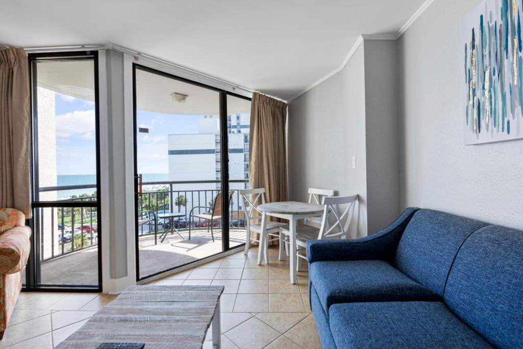 d'un salon avec un canapé bleu et d'un balcon. dans l'établissement Hosteeva 1-bedroom Meridian Plaza Condo with Ocean View, à Myrtle Beach