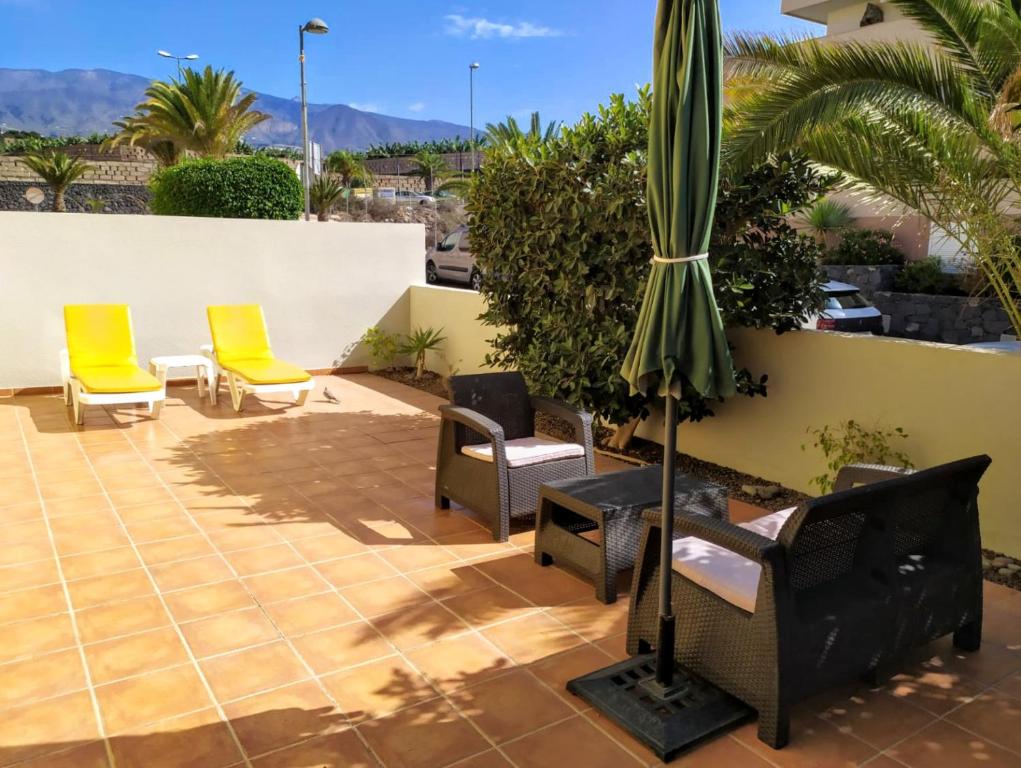 eine Terrasse mit Stühlen und einem Sonnenschirm in der Unterkunft Apartamento HAKUNA MATATA con gran terraza, planta baja in Playa de San Juan