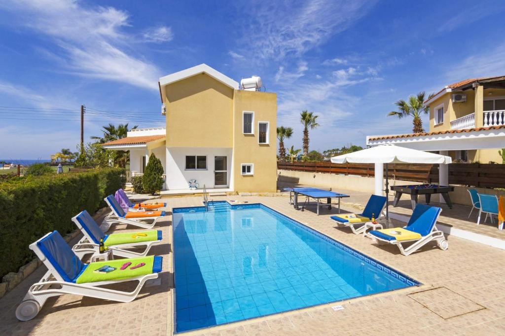 uma piscina com cadeiras e uma mesa e uma casa em Villa Azalea by Villa Plus em Pegeia ou Pegya