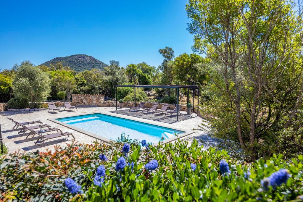 una piscina en un jardín con flores y árboles en Villa 18, en Porto Vecchio