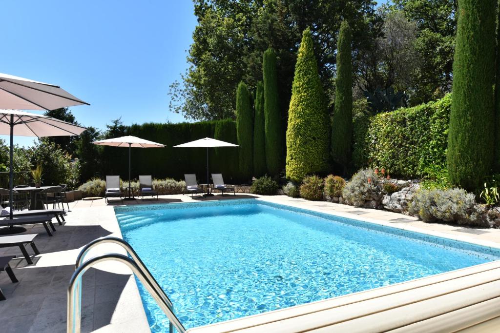 una piscina en un jardín con árboles y arbustos en Terre d'Orizon, en Tourrettes-sur-Loup