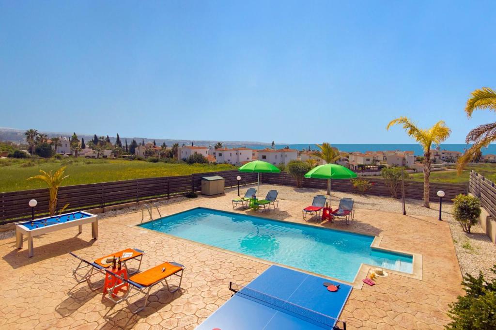 a swimming pool with chairs and umbrellas on a patio at Villa Kassiopeia by Villa Plus in Peyia