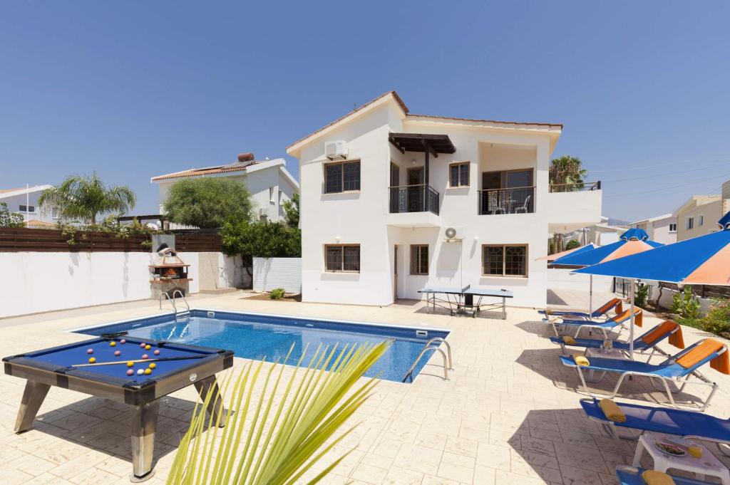 eine Villa mit einem Pool mit einem Tisch und Stühlen in der Unterkunft Villa Katina by Villa Plus in Peyia