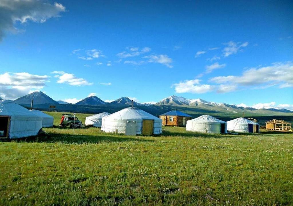 um grupo de tendas num campo com montanhas ao fundo em Doloon Uul em Turt