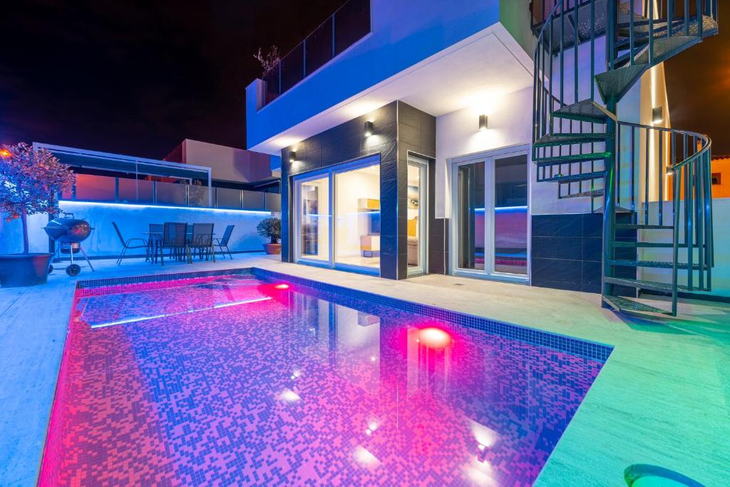 una piscina con luces rojas en una casa en New villa with rooftop terrace and pool, en Daya Nueva