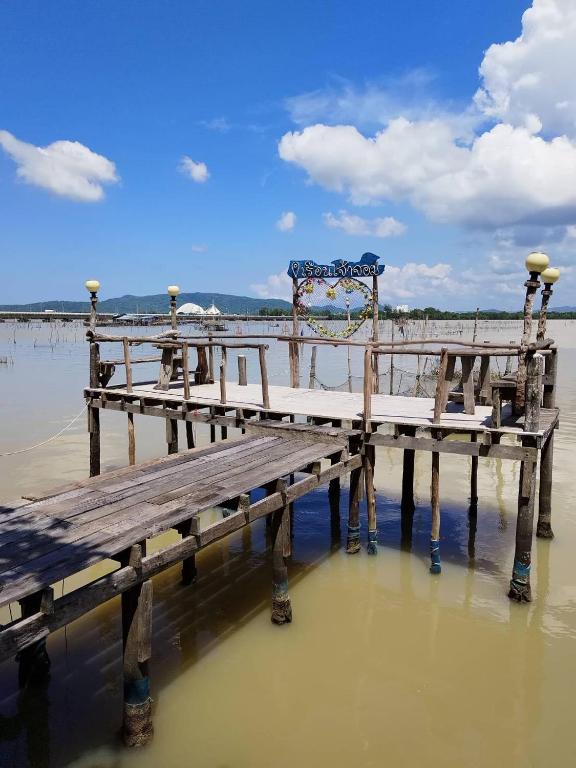 a wooden bench sitting on a pier in the water at โฮมสเตย์เรือนเจ้าจอม in Ban Bo Hin