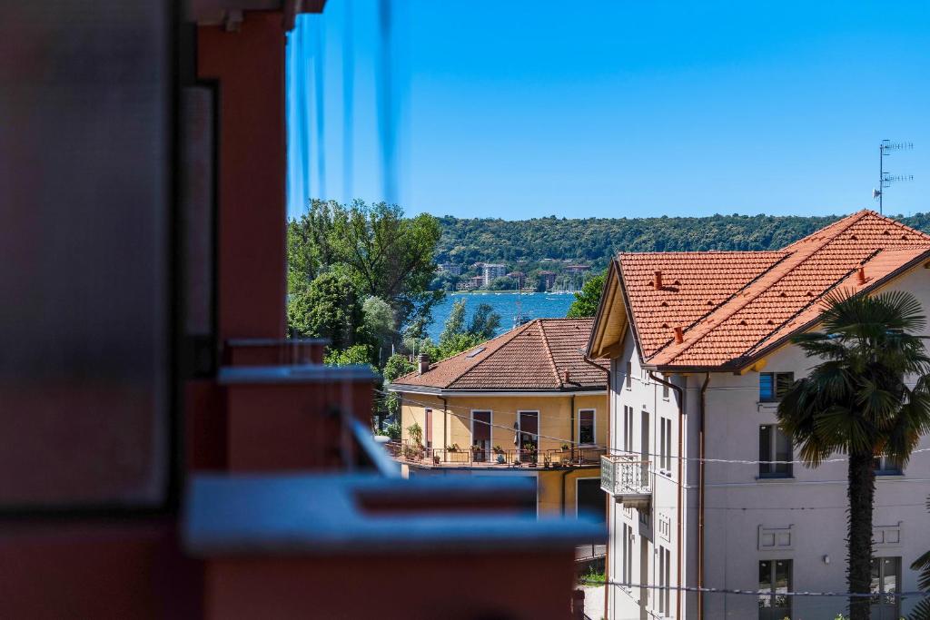 Blick auf Gebäude und eine Palme aus dem Fenster in der Unterkunft Iris Apartment Lago Maggiore in Angera